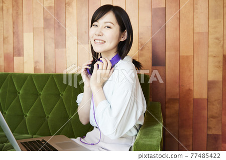 A woman sitting on the sofa watching a video on her computer 77485422