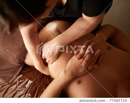 Asian man receiving a stomach massage Asian man receiving a stomach massage 77485729