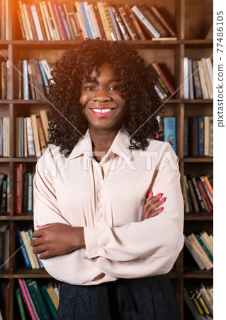 African american woman on the background of shelves with books, sunlight African american woman on the background of shelves with books, sunlight 77486105