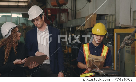 business engineering in hardhats discuss information on laptop computer 77486702