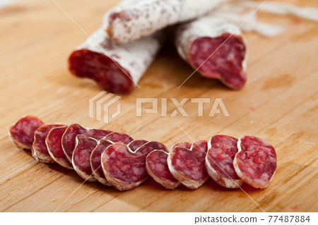 Slicing delicious Spanish smoked sausage fuete Slicing delicious Spanish smoked sausage fuete 77487884