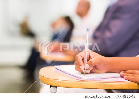 Closeup of female hand taking notes during lecture Closeup of female hand taking notes during lecture 77488545