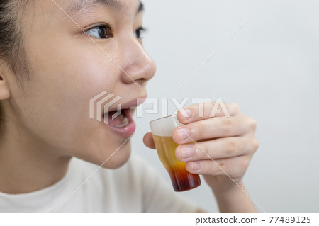 Asian lady girl rinsing the mouth or gargling with medicine of medical disinfectant,protect against the Coronavirus COVID-19 in throat,disinfection of the oral cavity or bad breath,pharyngitis concept 77489125