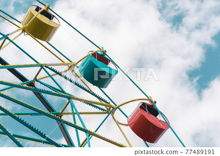 Ferris wheel under blue sky. Summer city park 77489191