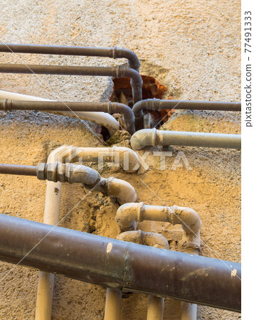 chaotic overlapping pipes on a plastered ocher wall color 77491333