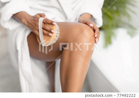 Unrecognizable African Woman Dry Brushing Legs Making Massage In Bathroom Unrecognizable African Woman Dry Brushing Legs Making Massage In Bathroom 77492222