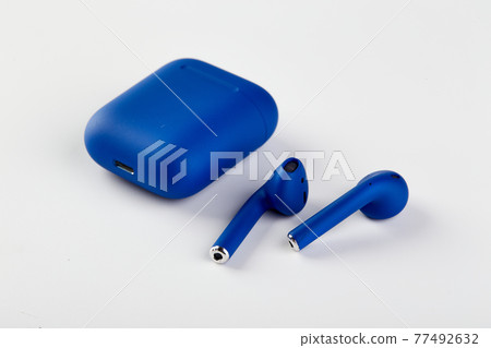 Blue Wireless headphones in charging case close-up on white background Blue Wireless headphones in charging case close-up on white background 77492632