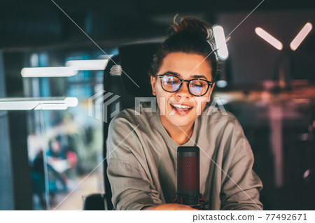 Young pretty woman broadcasting a podcast show remotely Young pretty woman broadcasting a podcast show remotely 77492671