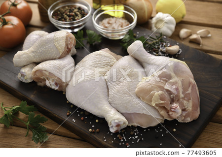Fresh raw chicken thighs with ingredients for cooking on a wooden cutting board 77493605