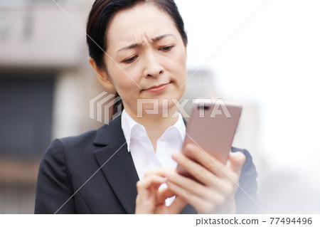 在戶外使用智能手機的女商人 在戶外使用智能手機的女商人 77494496