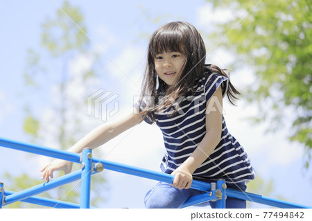 Elementary school girl climbing a jungle gym (6 years old) Elementary school girl climbing a jungle gym (6 years old) 77494842