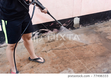 Worker cleaning dirty floor with high pressure washer. Worker cleaning dirty floor with high pressure washer. 77496333