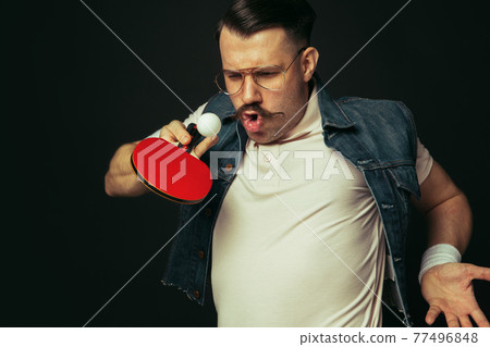 Young caucasian man playing tennis isolated on black studio background in retro style, action and motion concept 77496848