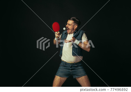 Young caucasian man playing tennis isolated on black studio background in retro style, action and motion concept 77496892