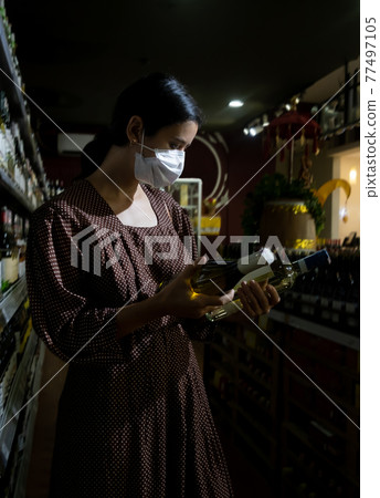 Alarmed female wears medical mask against coronavirus while shopping in store- health, safety and pandemic concept - young woman wearing protective medical mask for protection from virus 77497105