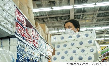 Alarmed female wears medical mask against coronavirus while buying tissues or toilet papers- health, safety and pandemic concept - young woman wearing protective medical mask for protection from virus 77497106