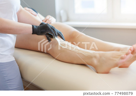 Hands in rubber gloves close-up. doctor puts wax, honey. medic is preparing for depilation. Concept of medicine, health care, beauty industry, hair removal, natural material. Copy space 77498079