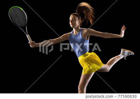 Young caucasian woman playing tennis isolated on black studio background in action and motion, sport concept 77500830