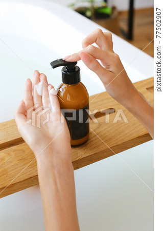 Woman's holding botles with spa cosmetics in bathroom. Beauty blogger, salon therapy, minimalism concept, copyspace Woman's holding botles with spa cosmetics in bathroom. Beauty blogger, salon therapy, minimalism concept, copyspace 77502907