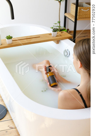 Woman's holding botles with spa cosmetics in bathroom. Beauty blogger, salon therapy, minimalism concept, copyspace 77502910