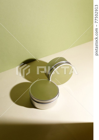 White cream in round aluminum metal tin on neutral background. Natural cosmetic product. Face and body skin care, cosmetic products. White cream in round aluminum metal tin on neutral background. Natural cosmetic product. Face and body skin care, cosmetic products. 77502913