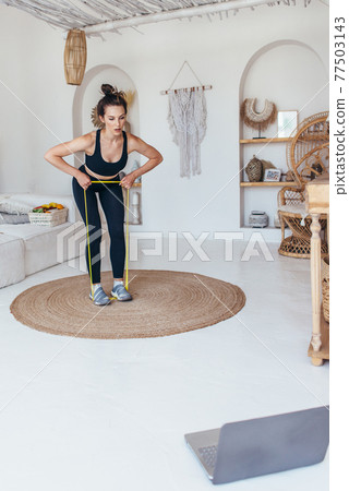 Woman working out at home with elastic band 77503143
