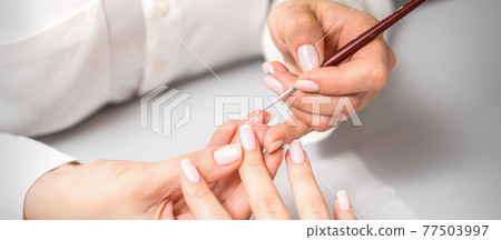 Manicurist drawing nail with thin brush 77503997