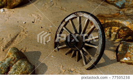 Old wooden cart wheel at sand beach 77505238
