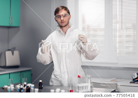 A young male scientist testing a Chemical in a science Laboratory. The scientistific analysis of chemicals for New Innovation. Science Laboratory Concept A young male scientist testing a Chemical in a science Laboratory. The scientistific analysis of chemicals for New Innovation. Science Laboratory Concept 77505418