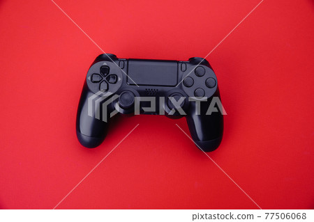 Black gamepad isolated on a red background. Top view. Gaming concept Black gamepad isolated on a red background. Top view. Gaming concept 77506068
