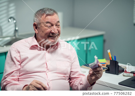 A happy old man is giving money to the doctor for his medical consultation. Private medical practice 77506282