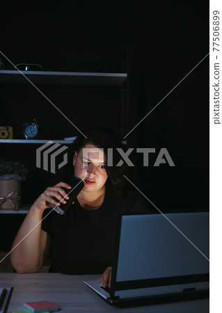 Focused woman drinking energy drink at night Focused woman drinking energy drink at night 77506899