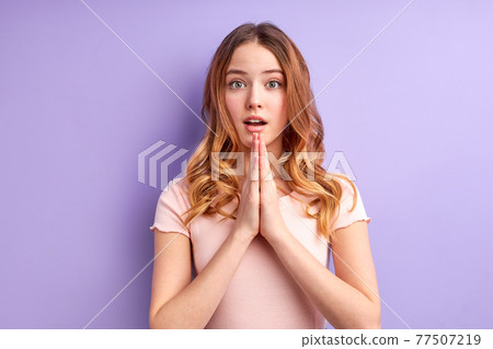 Attractive blonde girl in casual clothes prays for wellness of family, keeps palms pressed together in praying gesture, dreaming Attractive blonde girl in casual clothes prays for wellness of family, keeps palms pressed together in praying gesture, dreaming 77507219