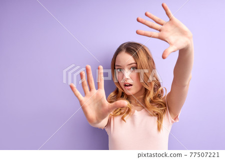 Teen girl over isolated purple background scared with arms up like something falling from above Teen girl over isolated purple background scared with arms up like something falling from above 77507221