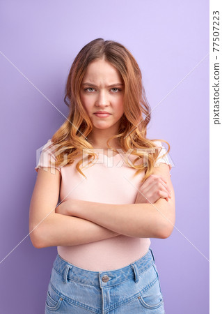 upset and offended teenage girl with crossed arms isolated on purple background upset and offended teenage girl with crossed arms isolated on purple background 77507223