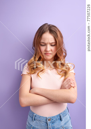 sad and offended teenage girl with crossed arms isolated on purple background sad and offended teenage girl with crossed arms isolated on purple background 77507226