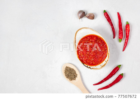 Hot chili pepper sauce paste harissa. Adjika on a white background. Traditional Tunisia, Georgian and Arabic cuisine. Homemade rose harissa in a bowl. Hot chili pepper sauce paste harissa. Adjika on a white background. Traditional Tunisia, Georgian and Arabic cuisine. Homemade rose harissa in a bowl. 77507672