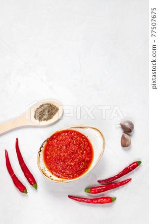 Hot chili pepper sauce paste harissa. Adjika on a white background. Traditional Tunisia, Georgian and Arabic cuisine. Homemade rose harissa in a bowl. Hot chili pepper sauce paste harissa. Adjika on a white background. Traditional Tunisia, Georgian and Arabic cuisine. Homemade rose harissa in a bowl. 77507675