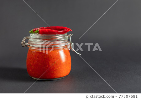 Hot chili pepper sauce paste harissa. Adjika. Traditional Tunisia, Georgian and Arabic cuisine. Homemade rose harissa in a glass jar. 77507681