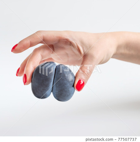 Trendy ugly food concept. Purple ugly plum in a woman's hand on a white background. Fruit with a strange shape. The problem of food waste 77507737