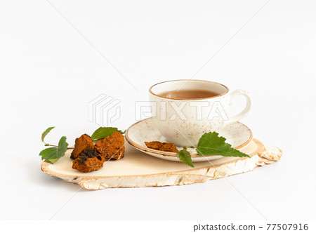 Chaga tea on a wooden birch board isolated on a white background. Traditional Russian drink. Chaga tea on a wooden birch board isolated on a white background. Traditional Russian drink. 77507916