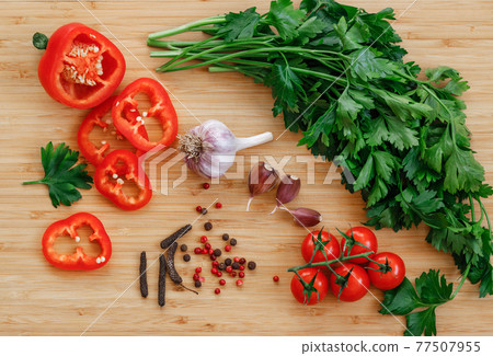 Fresh vegetables on the table. Food background. Flat lay. Cherry tomatoes, a bunch of parsley, chopped red pepper, garlic and spices on a wooden chopping Board. Ingredients for pickling or salads Fresh vegetables on the table. Food background. Flat lay. Cherry tomatoes, a bunch of parsley, chopped red pepper, garlic and spices on a wooden chopping Board. Ingredients for pickling or salads 77507955