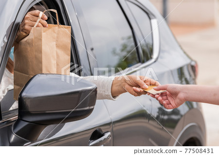 Females exchanging a credit card through a car window Females exchanging a credit card through a car window 77508431