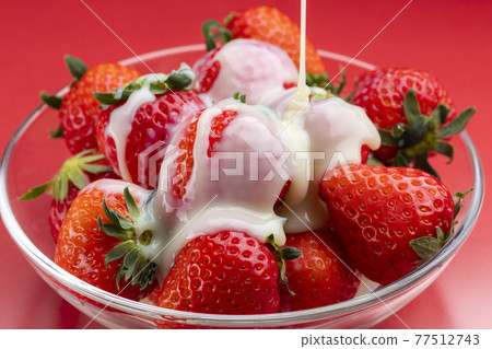 Sprinkle condensed milk on the strawberries on a glass bowl Sprinkle condensed milk on the strawberries on a glass bowl 77512743