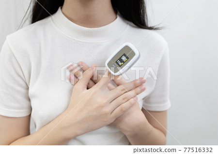 Hand of lady girl with fingertip pulse oximeter on finger for examination of the lung disease,checking for Coronavirus COVID-19 infection from oxygen saturation at home,measuring heart rate (pulse) 77516332