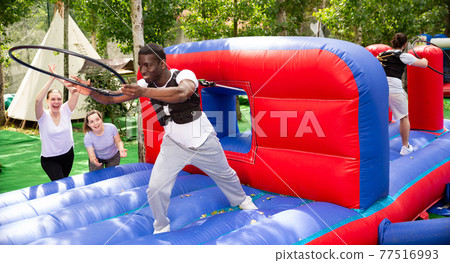 African man collecting hoops on inflatable trampoline 77516993