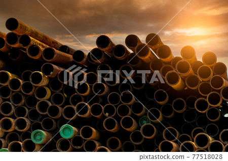 Pile of old rusty round metal industrial pipe. Steel pipe stack during sunset. Industrial material. Metal corrosion. Stack of round rusty tube abstract background. Old iron pipe warehouse of factory 77518028