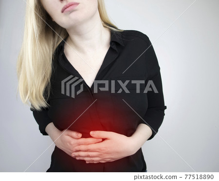 A woman holds on to his stomach. Pain in the abdominal cavity. The concept of diseases of the stomach and digestive system 77518890