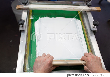 Serigraphy silk screen print process in clothes factory. Frame, squeegee and plastisol white color paint 77519690