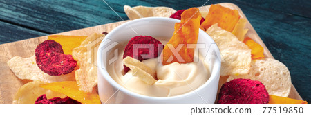 Vegetable chips with a dip panorama on a dark blue wooden background 77519850